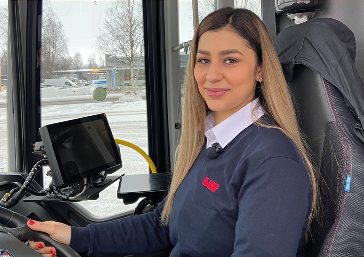 Bild på en av våra kvinnliga förare på LLT där hon sitter bakom ratten på en buss.